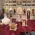 Father Vjekoslav, who is wearing white vestments, stands in front of the open Royal Doors, facing parishoners. He is holding a censor and using it to bless the congretation.