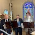 Four men who are part of the choir singing behind music stands.