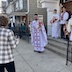 Fr. Aleksey and parishoners in front of the church. Four altar servers are standing outside in front of the entrance of the church, with the closed doors behind them. Fr. Aleksey is blessing the congregation and church as he stands on the sidewalk, down three steps from the altar severs. He's holding the censor in his right hand and a bouquet of candles in his left. He and the altar servers are wearing white vestments.