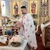 Fr. Aleksey is standing on the far side of a table near the front of the church, and he's blessing Pascha baskets on the table. The table is covered with a white table cloth.