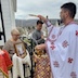Fr. Aleksey, in the right half of the frame, is blessing the woman from the previous photo. She appears in the lower left corner of the frame, and one of the men and the altarboy are also visible. A trail of water is streaming from the golden bowl to the Fr. Aleksey's brush as he blesses the group, and individual water droplets can be seen.
